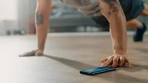 Trainingsprogramme Mann mit Handy im Fitnessstudio
